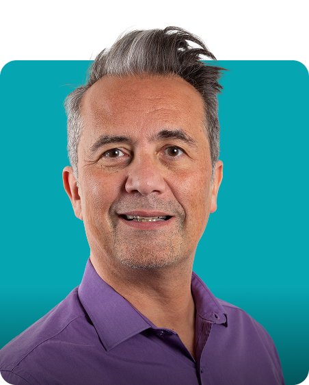 Man smiling against teal background in a purple shirt