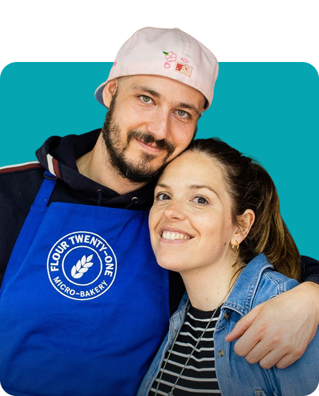 Couple Wearing Bakery Apron Smiling Against Blue Background